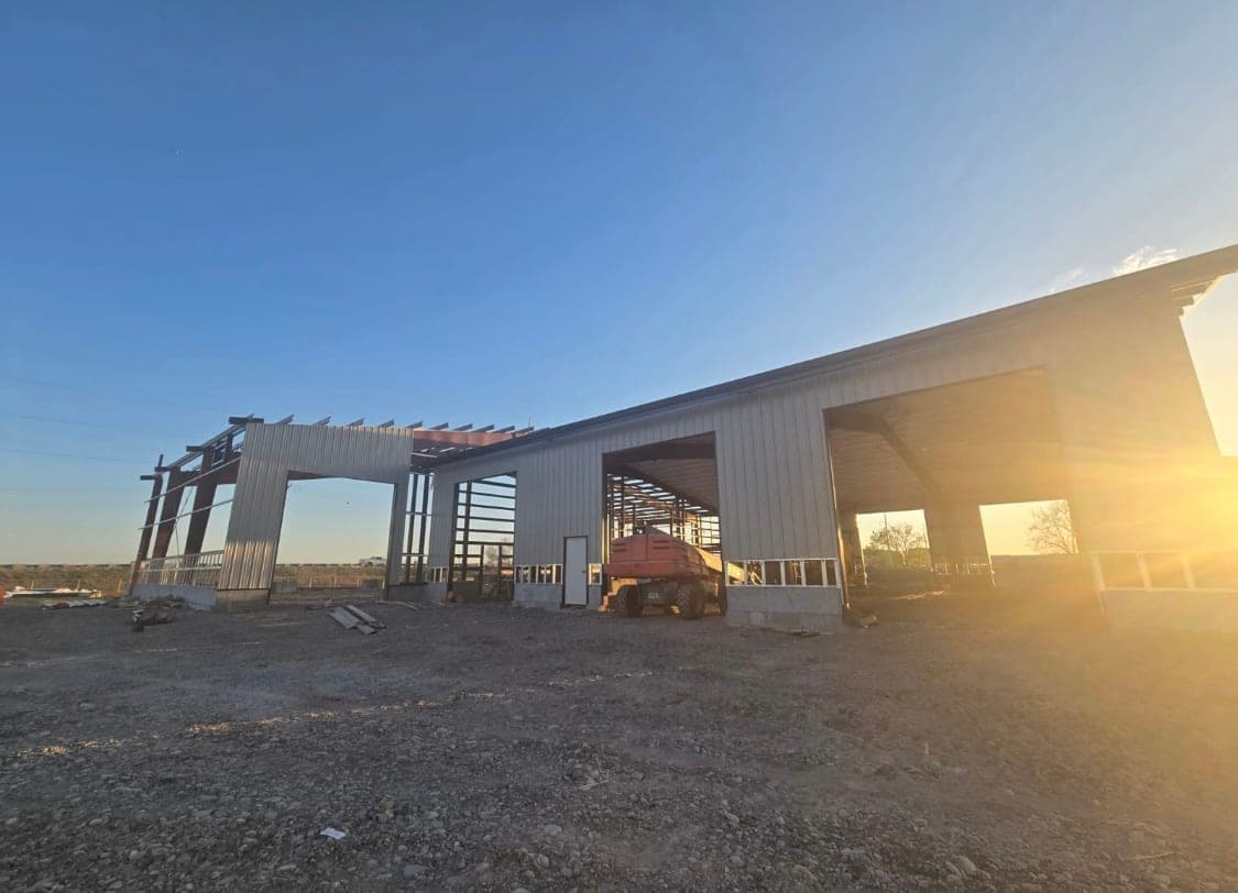 Large steel office and shop shell under construction at sunset in Idaho